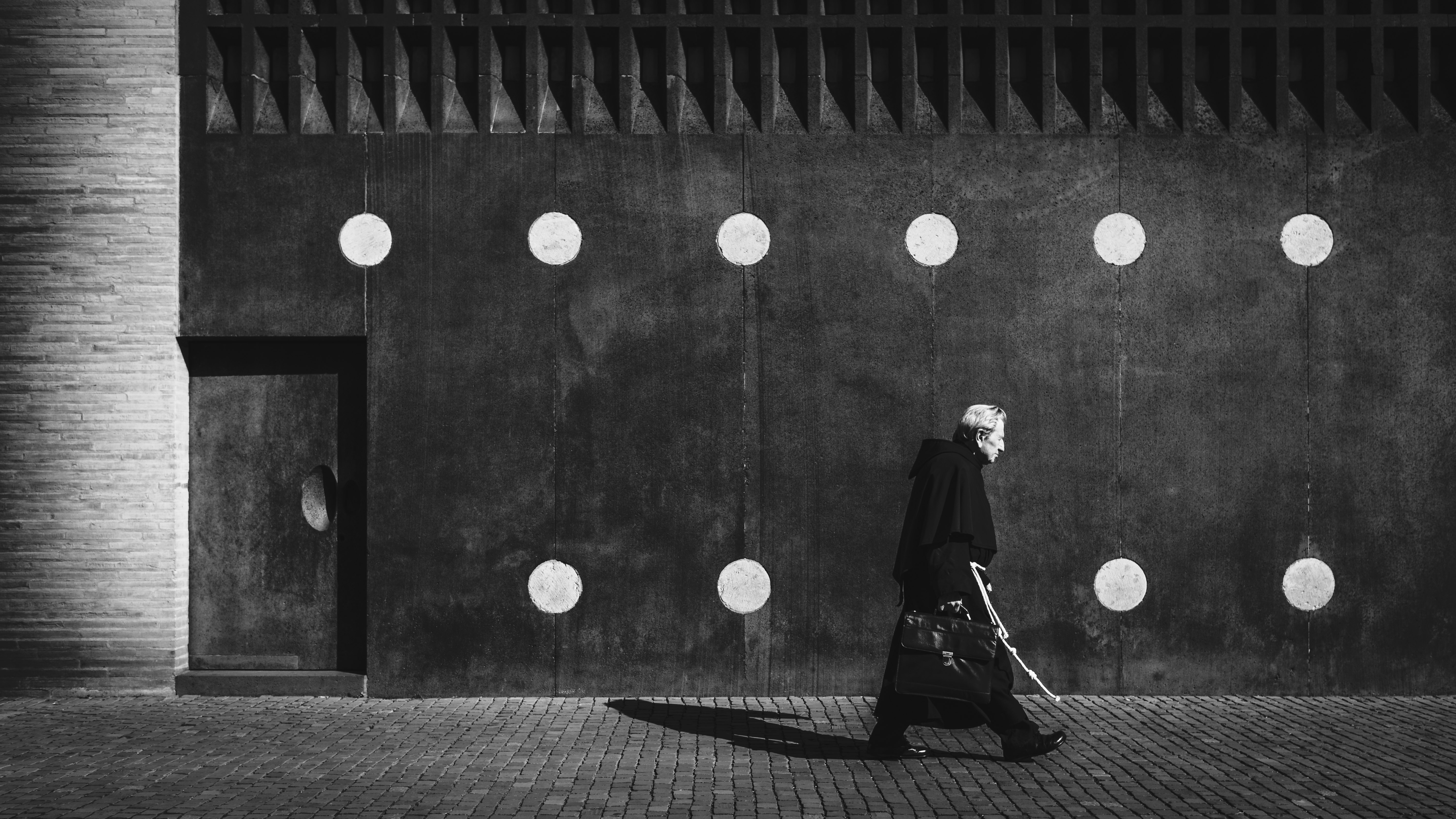 man in black coat walking on sidewalk during daytime